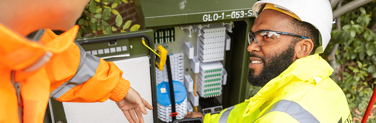 Image of a Kier worker interacting with a colleague in front of a roadside fuse box.