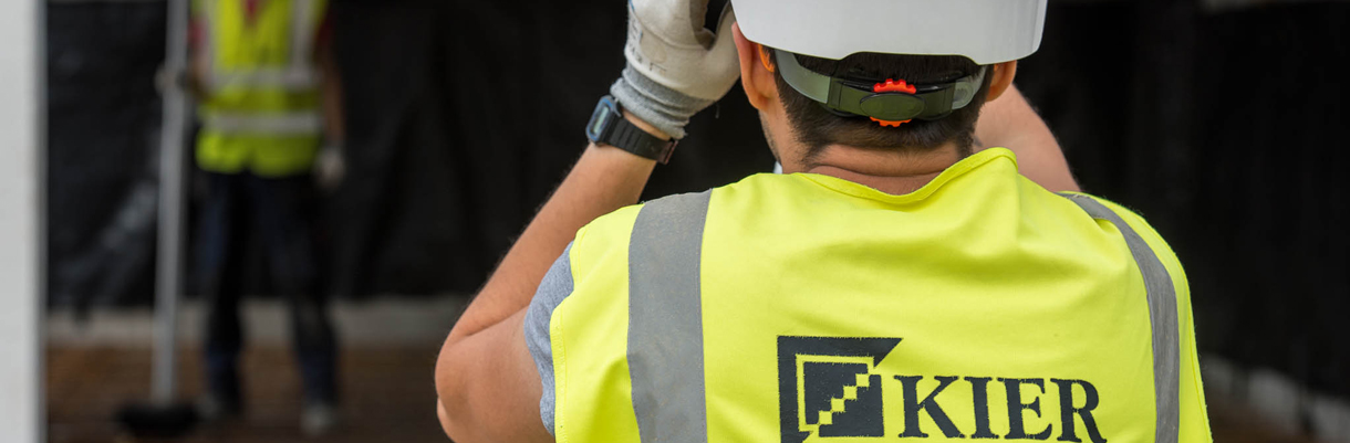 Image of a Kier employee in a high visibility vest taking an image of the worksite